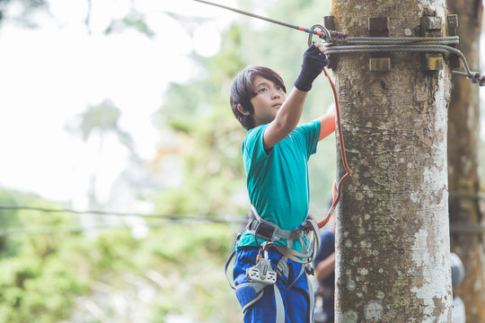 active brave boy enjoying outbound climbing at adventure park on
