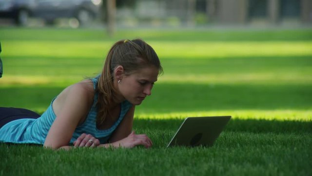 Portrait of a woman using laptop in the grassy park