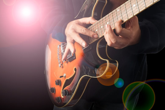 A man is playing guitar with lighting effect.