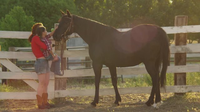 Mom with daughter petting a horse