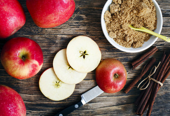 Apples, pears, cinnamon sticks and brown sugar on wooden backgro