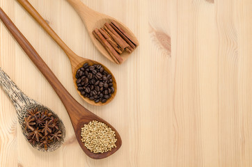 Cinnamon sticks, star anise, coriander seed and coffee grains on wooden spoon, seasoning ingredients for cooking or baking.