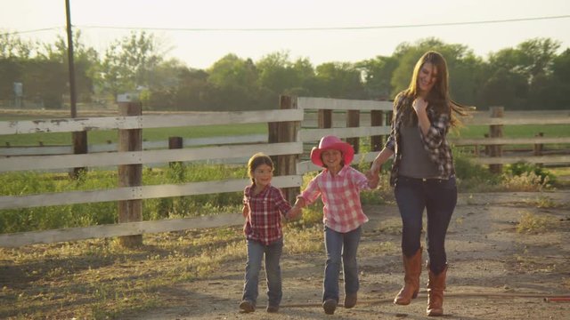 Young woman and two little girls slow motion running on ranch