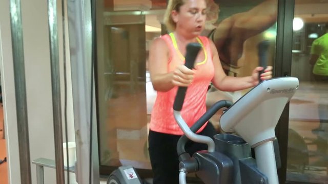 Woman trains on stepper machine in gym. Concept of health and fitness.