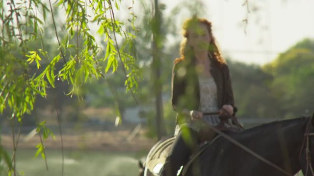 Blur in to young woman riding horse through ranch farm