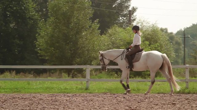 Girl riding on a horse arena on the outside in the country