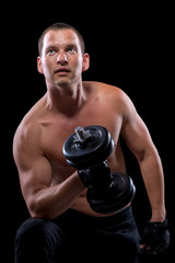 bodybuilder with dumbbell, shot on a black background