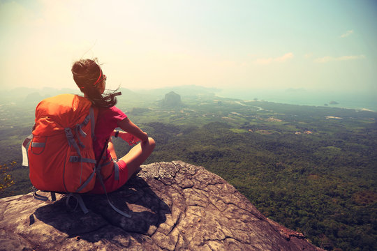 young woman hiker enjoy the view on mountain peak cliff