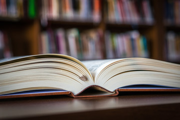 Open book on the table in a library and bookshelf