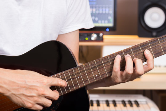 musician hands playing acoustic guitar in recording studio