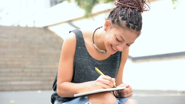 Woman sitting on the stair and write down notes in the notebook