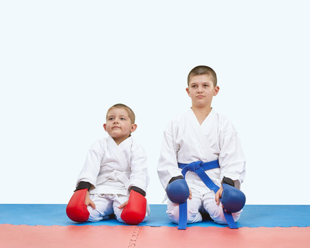 Brothers athletes sitting on a mats in karate pose