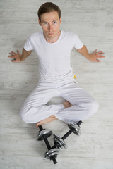 Man sitting on the floor with dumbbells. Resting time.