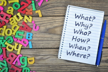 Questions text on notepad and magnetic letters