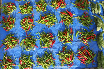 Kupki czerwonej i zielonej papryczki chili na niebieskim tle na bazarze ulicznym - obrazy, fototapety, plakaty