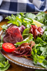 Dried beef bresaola. Salad bresaola arugula baby spinach tomatoes lime and cheese parmesan.