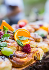 Catering buffet food outdoor. Cakes colorful fresh fruits berries oranges grapes and herb decorations.