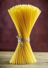 Bunch of spaghetti on wooden table -  purple background.