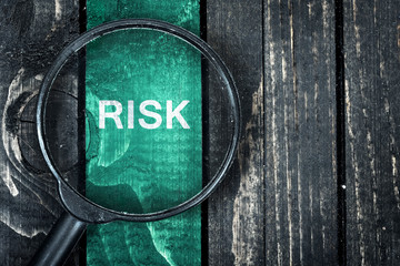 Risk text painted and magnifying glass on table