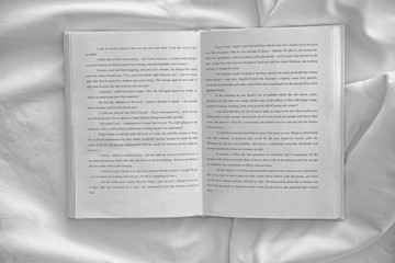 Opened book on white crumpled sheet