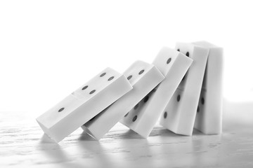 Line of dominoes falling on light wooden background