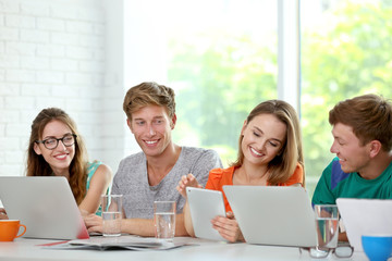 Young people with gadgets sitting at table