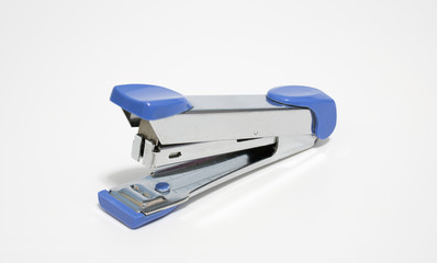 Old blue stapler on white, soft focus