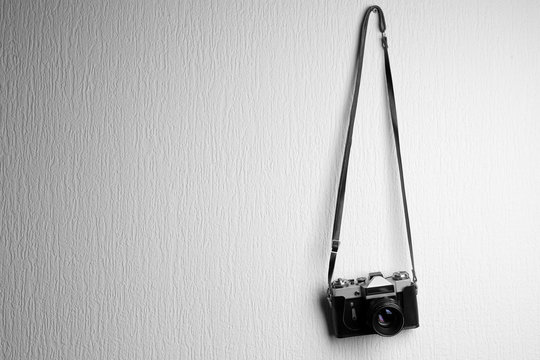 Vintage camera hanging on white textured background