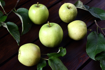 Green fresh apples with leaves on a dark background