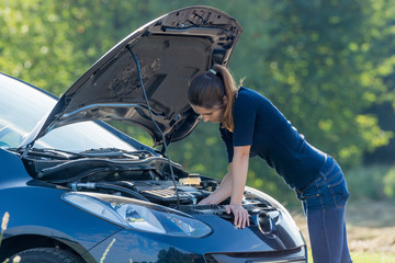frau schaut verzweifelt in den motorraum