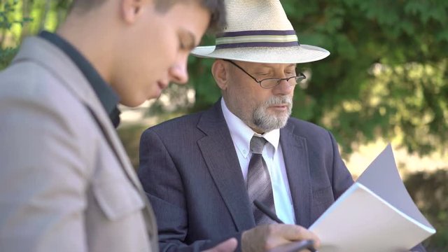 Old and young workers writing dowm in notebook on the street. 4K