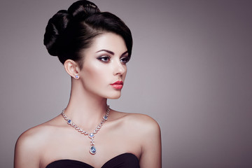 Fashion portrait of young beautiful woman with jewelry and elegant hairstyle. Brunette girl....