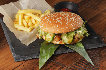 Cheeseburger with french fries and sauce. Hamburger on a brown wooden background