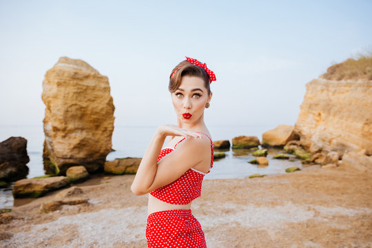 Happy pretty pinup girl in red swimsuit sending a kiss
