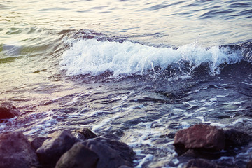 Strong sea wave splashing on the rocky shores; selective focus; toned image