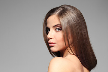 Young woman with healthy hair on color background