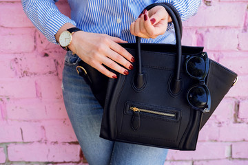 Close up black leather bag in hand of fashion woman.