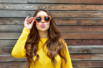 Beautiful smiling brunette woman in sunglasses blowing lips kiss