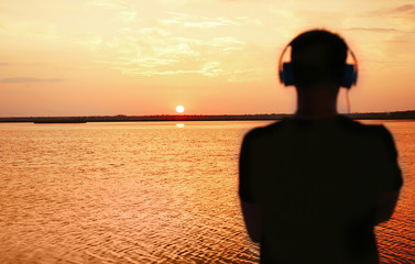 Silhouette of man with headphones on sunset sky background