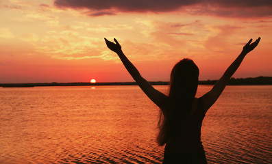 Silhouette of woman on sunset sky background