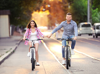 Young lovely couple riding bicycles on street