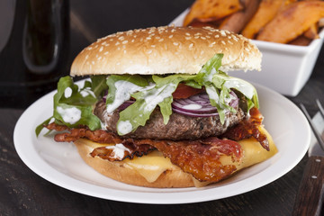 juicy  bacon cheese bbq burger on wooden table with fries