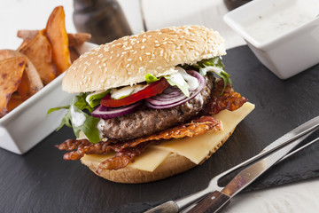 juicy  bacon cheese bbq burger on wooden table with fries