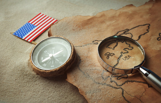 Old map with compass, American flag and magnifier on sand. Happy Columbus day concept - Powered by Adobe