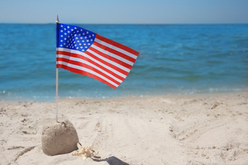 American flag with sand castle on beach