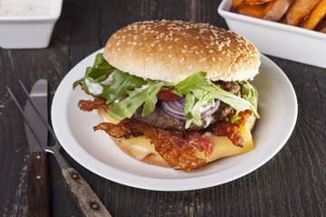 juicy  bacon cheese bbq burger on wooden table with fries
