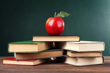 School books with apple on blackboard background