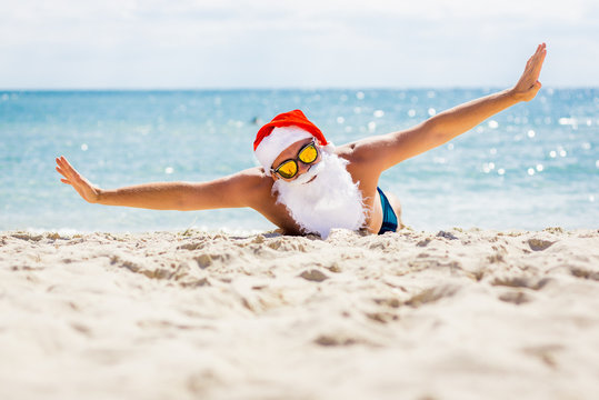 Pretty Santa Claus in sunglasses on the beach with ocean views