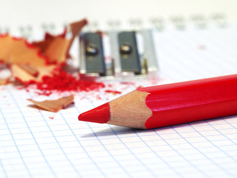 sharpened red pencil with shavings and sharpener in background, shallow depth of field