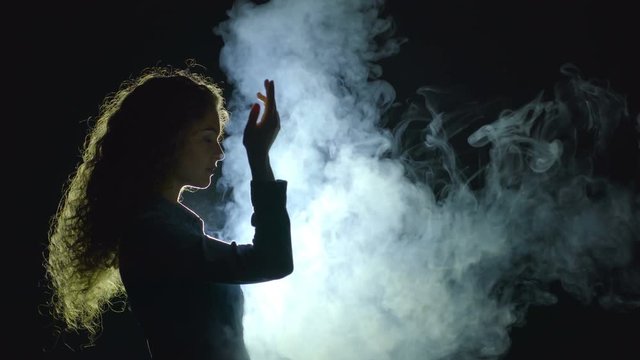 The girl stand on the background of a smoke. Real time capture